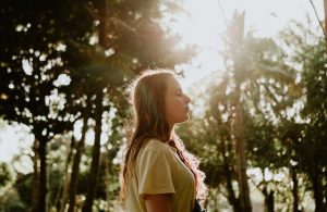 woman eyes closed in a forest with the sunshine on her